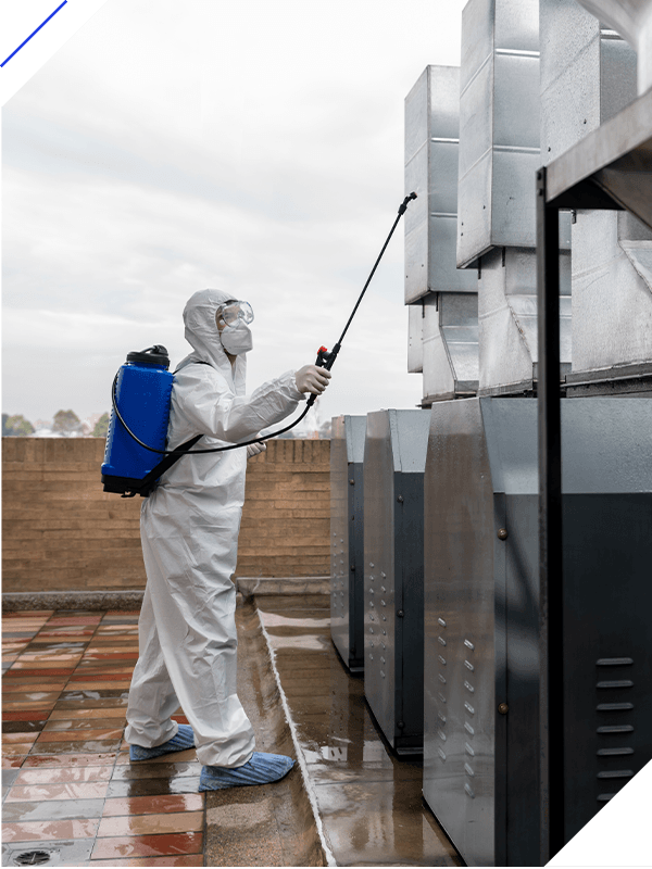 Professional cleaner disinfecting air vents at a factory